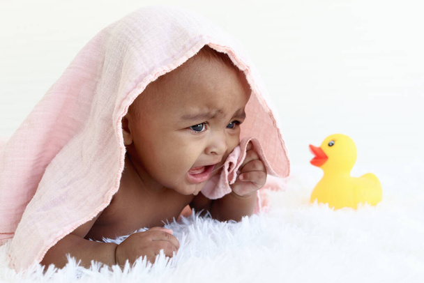 Ritratto di adorabile bambino afroamericano strisciante di sei mesi coperto di asciugamano dopo il bagno, felice sorridente dolce bambina che gioca con il giocattolo dell'anatra gialla, l'infanzia e il concetto di cura del bambino. - Foto, immagini