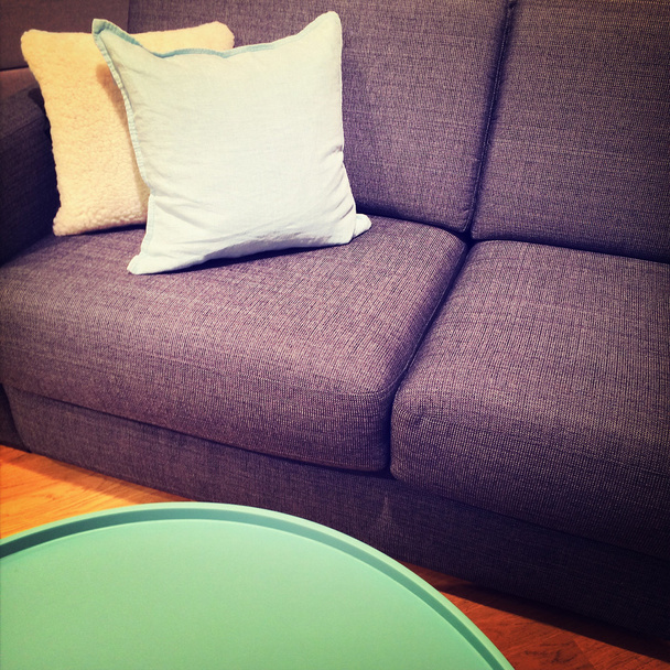 Зеленый журнальный столик и диван с подушками
 - Фото, изображение