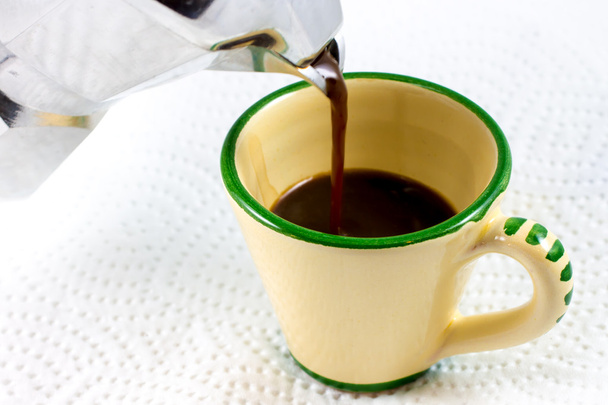 налить кофе в чашку у кастрюли с мокой
 - Фото, изображение