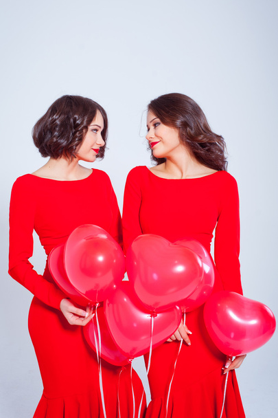Dvě krásné mladé ženy v dlouhé červené šaty s balónky - Fotografie, Obrázek