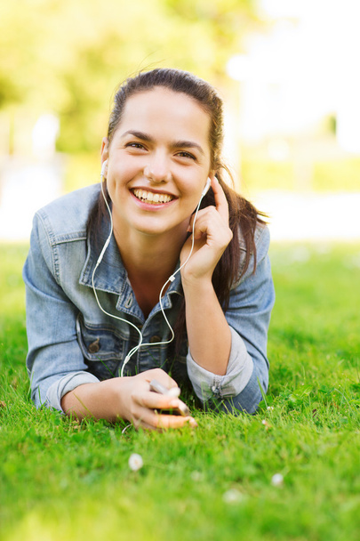 smiling young girl with smartphone and earphones - Photo, Image
