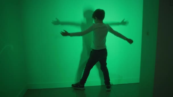 επιστήμη και φυσική, χαρούμενο παιδί παίζει με εφέ φωτός και αφήνει σκιά στον τοίχο σε ένα διαδραστικό δωμάτιο - Πλάνα, βίντεο
