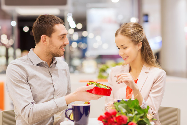 happy couple with present and flowers in mall - Foto, Imagem