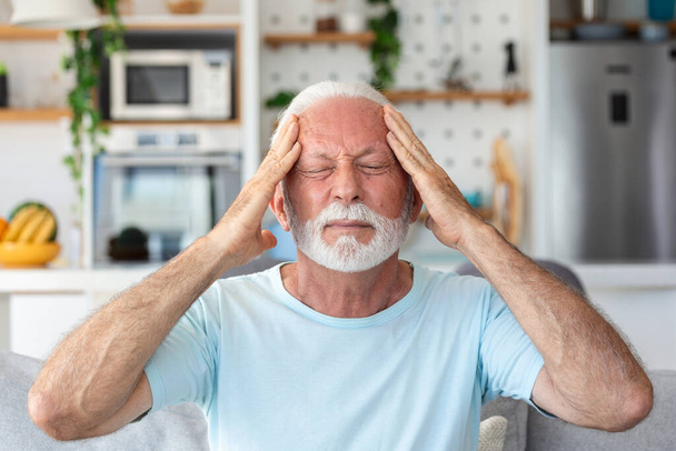 頭痛だ。片頭痛に苦しむシニア男性痛みマッサージ寺院自宅で座っています.ヘルスケア、高齢者の健康問題の概念 - 写真・画像