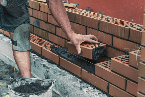 Trabajador o albañil tendiendo ladrillos. Constructor hace ladrillo en el sitio de construcción, de cerca en las manos. - Foto, imagen