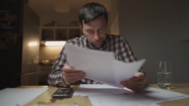 Financial problems. Sad man trying to find solution to taxes and debts at home in kitchen. Brainstorming ways of solving money troubles. Stressed male calculates costs, try to keep money in savings.  - Footage, Video