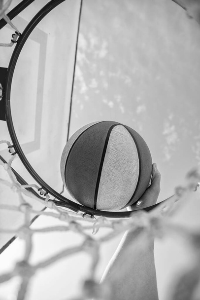 μπασκετμπολίστας ρίχνει την μπάλα στο στεφάνι, κοντινό πλάνο, αθλητική επιτυχία. - Φωτογραφία, εικόνα