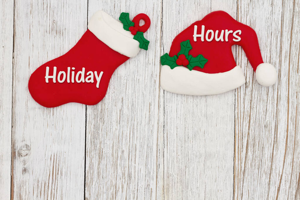 Holiday Hours message with Santa hat and Christmas stocking on weathered wood with space for your Christmas opening hours - Photo, Image