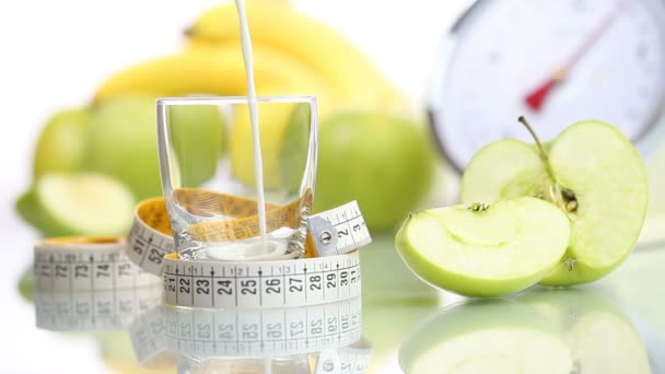 Dieta jedzenie rozlane mleko szkła, owoce jabłko licznik wagi - Materiał filmowy, wideo