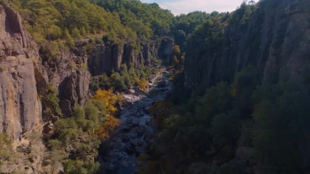 Flug über das flache Flussbett zwischen grünen Felsen. Berglandschaft. Blauer Himmel und Wolken. Videoaufnahmen von Drohnen aus der Luft. Hochwertiges 4k Filmmaterial - Filmmaterial, Video