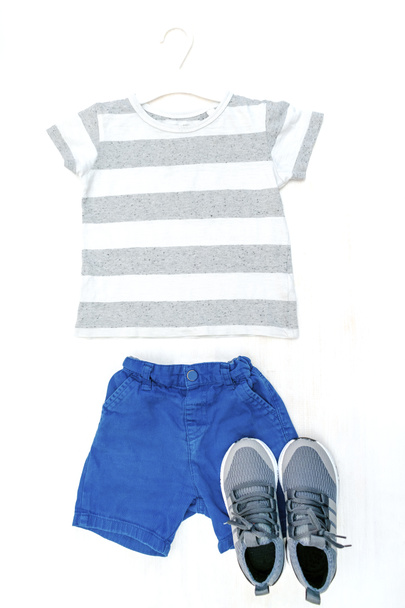 Summer babies blue gray clothes and accessories with t shirt, shorts,sneakers. Modern fashion kids casual outfit.Set of children's clothing for spring. Flat lay, top view,overhead,mockup. - Photo, Image