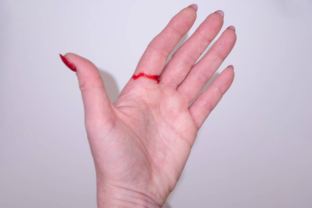 Kadın elini kağıt ve hediyeyle kesti. Elinde kırmızı kan vardı. Yüksek kalite fotoğraf - Fotoğraf, Görsel
