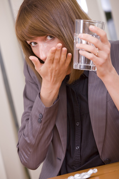 vrouw nemen pillen door werk - Foto, afbeelding