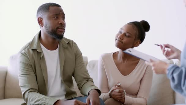 Aile sevgisi ve destek. Depresyondaki Afrikalı Amerikalı adam ofisteki psikoterapistle konuşuyor, onu destekleyen ve kucaklayan karısı, çekim takibi, yavaş çekim, serbest alan - Video, Çekim