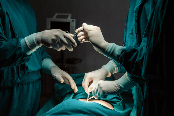 Imagem da equipe cirúrgica realizar operação cirúrgica, enfermeira entregar tesoura estéril ao cirurgião como apoio e cooperativa no conceito sala de operação. - Foto, Imagem