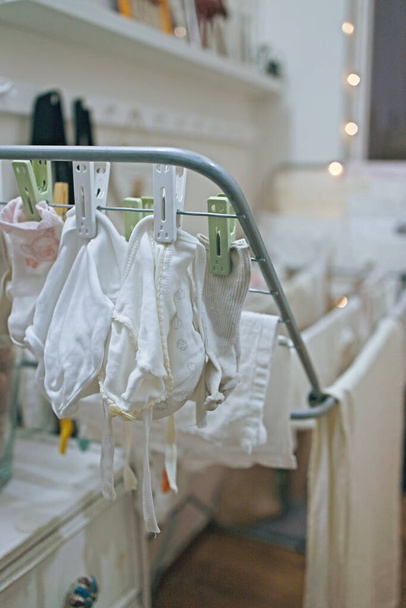 Baby 's kleren, bodysuits en broeken worden gedroogd na de wasserij. Organisatie en schoonmaak in de kinderkamer. - Foto, afbeelding