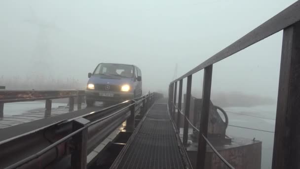 Samochód jeździ na most pontonowy na rzece, zima - Materiał filmowy, wideo