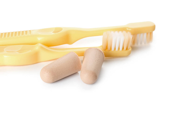Zahnbürsten und Ohrstöpsel auf weißem Hintergrund - Foto, Bild
