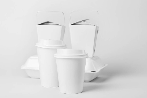 Copos de papel e diferentes recipientes de alimentos em fundo claro - Foto, Imagem