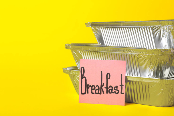 Stack of takeaway boxes and sticky note with word BREAKFAST on color background, closeup - Photo, Image