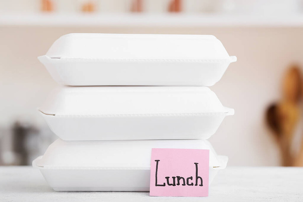 Conteneurs pour aliments et note collante avec mot LUNCH sur table blanche - Photo, image