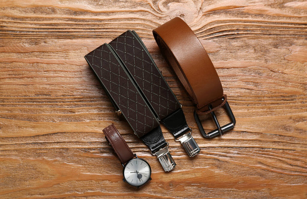 Orologio da polso, bretelle e cintura in pelle su fondo legno - Foto, immagini