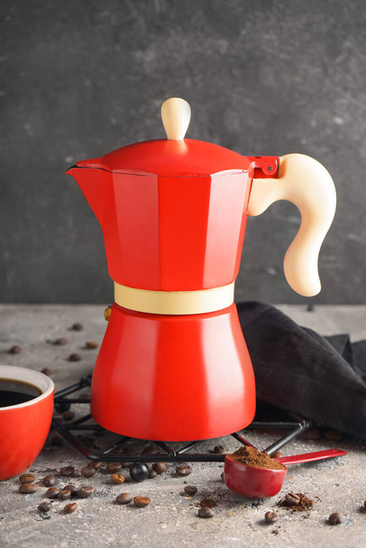 Geysirkaffeemaschine, Tasse Espresso, Bohnen und Serviette auf Tisch vor schwarzem Grunge-Hintergrund - Foto, Bild