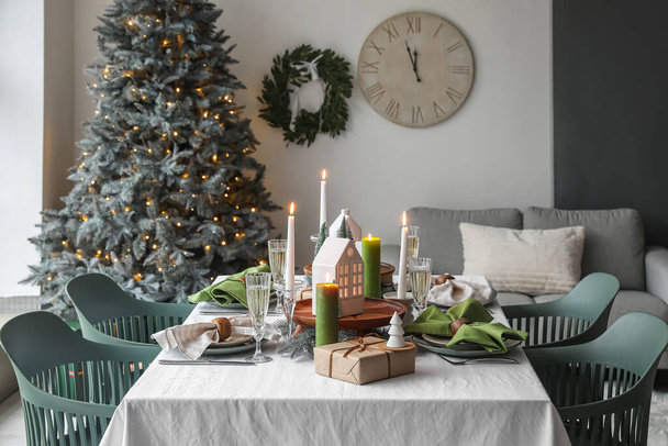 Christmas table setting with candle holders, presents and fir trees in dining room - Photo, Image
