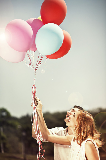 Young happy couple holding colorful ballons and smiling - Photo, Image