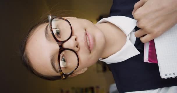 Smiley 10 éves szemüvegben és a kamerába néz. Függőleges 4k felvétel. - Felvétel, videó