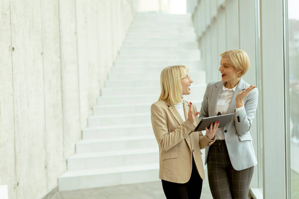 Zwei Geschäftsfrauen laufen mit Laptop und Handy im Büroflur - Foto, Bild