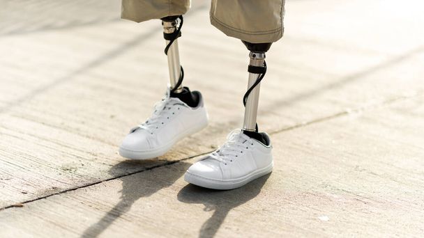 Veduta di un uomo che cammina con gambe protesiche e scarpe da ginnastica bianche - Foto, immagini