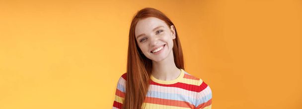 Příjemné charismatické mladé sebevědomé bezstarostné zrzka okouzlující dívka naklápění hlavy usmívat široce bílé zuby mluví ležérně dobrá nálada vyjádřit pozitivní šťastné emoce stojící oranžové pozadí. - Fotografie, Obrázek