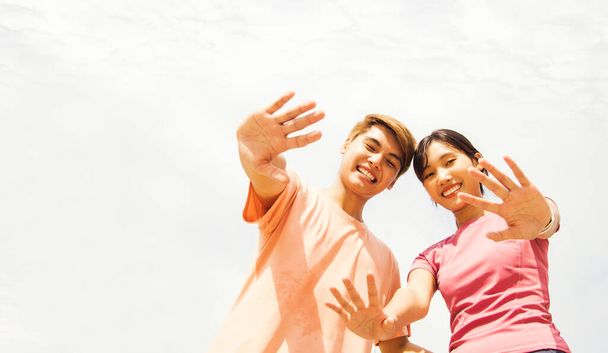 Glückliches Porträt junge asiatische Freundin und Freund winken Hallo vor dem Sport, gemeinsam Sport treiben lächelnd in die Kamera an einem sonnigen Tag: Sport und Freizeit Gesundheitskonzept. - Foto, Bild