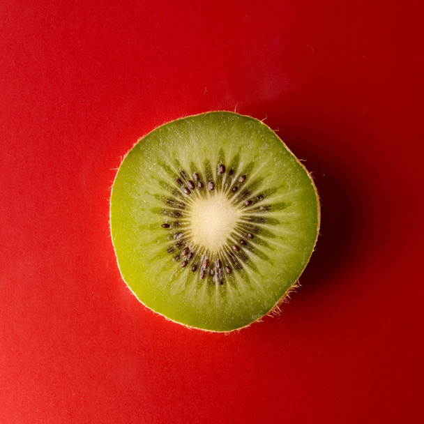 One slice of kiwi fruit isolated on red background, square shot - Zdjęcie, obraz