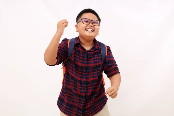 Cheerful asian school boy dancing and with clenched hands. Isolated on white background - Photo, Image