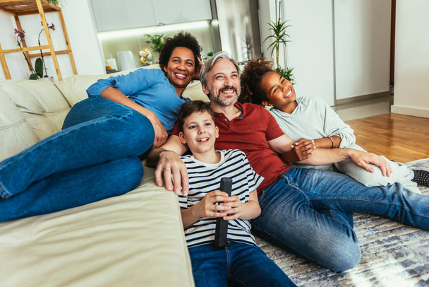 Jeune famille regardant la télévision ensemble à la maison et s'amusant ensemble
. - Photo, image