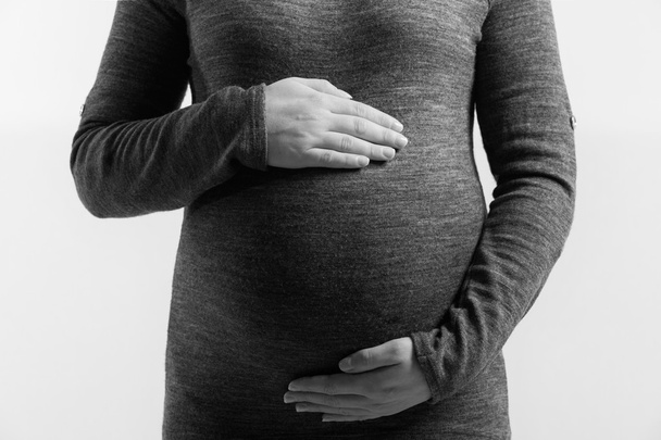 Image of pregnant woman touching her belly with hands  on white background - Zdjęcie, obraz