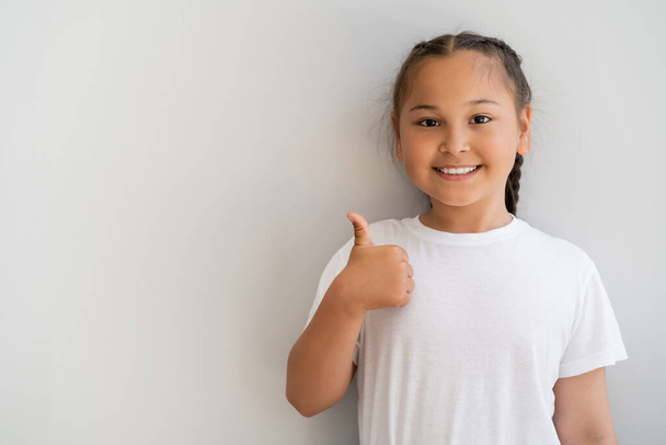 glimlachend aziatisch meisje tonen als gebaar en kijken naar camera thuis  - Foto, afbeelding