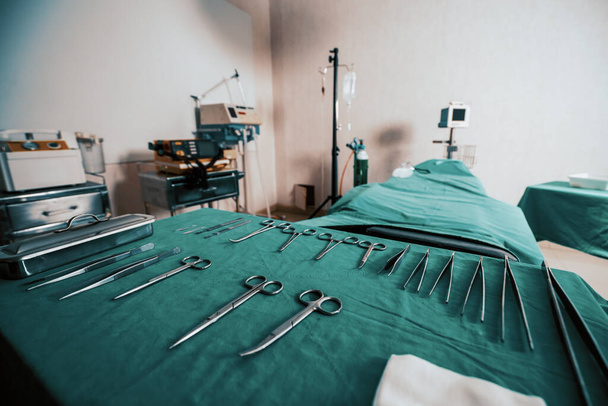 Sala de operaciones estéril en el hospital muestra conjuntos de equipos quirúrgicos médicos dispuestos en la mesa. Sala de cirugía con antecedentes de herramientas quirúrgicas para fines médicos. - Foto, imagen