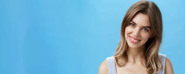 Περιμένετε-up πλάνο της γοητευτικής αυτοπεποίθηση αυθεντική γυναίκα αισθάνεται μεγάλη αποδοχή δική ατέλειες γέρνοντας το κεφάλι χαμογελώντας ευρέως στην κάμερα και δείχνει χαριτωμένο σπασμένα δόντια ποζάρουν πάνω από το μπλε φόντο - Φωτογραφία, εικόνα