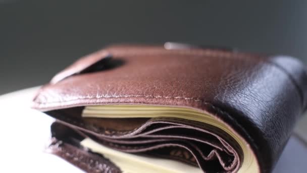 Gros plan d'un portefeuille brun avec des billets en dollars sur fond noir. Charges financières, dépenses, achats, économies accumulées. Vidéo 4k - Séquence, vidéo