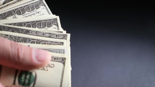 Feche as mãos masculinas contando notas de cem dólares no fundo preto. Um homem mostra muitos dólares americanos. Vídeo 4K - Filmagem, Vídeo
