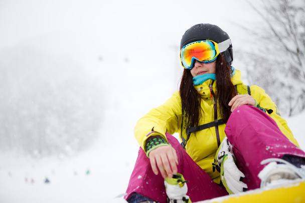 Snowboarder sitting on snow in high mountains - Фото, зображення