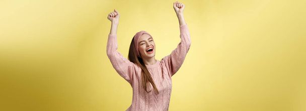 Позитивна селебція щасливої юної жінки, одягненої в випадковий светр, із задоволенням кричить: "Так, піднімаючи руки на перегонах і успішно стрибаючи в екстатичну радість". Копіювальний простір - Фото, зображення