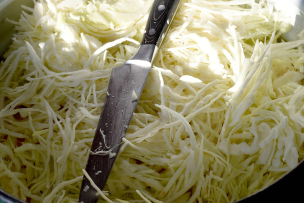 Ένα είδος τεμαχισμένου λάχανου και ένα ευρύ μαχαίρι που χρησιμοποιείται για να κόψει λάχανο. - Φωτογραφία, εικόνα
