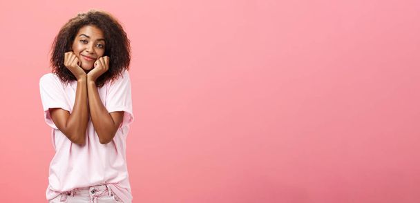 Мрійлива ностальгічна афроамериканська дівчина з кучерявою зачіскою, що сидить на голові на долонях і м'яко посміхається, ніби візуалізація або погляд на хлопця з любов'ю має почуття до друга
 - Фото, зображення