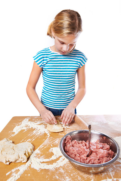 Girl kneads dough for pie on kitchen table isolated - Фото, зображення