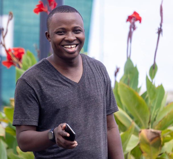een jonge Afrikaan krijgt goed nieuws van een telefoontje in een stadstuin - Foto, afbeelding