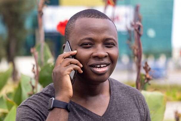 młody Afrykanin otrzymuje dobre wieści z telefonu biegnącego w miejskim ogrodzie - Zdjęcie, obraz